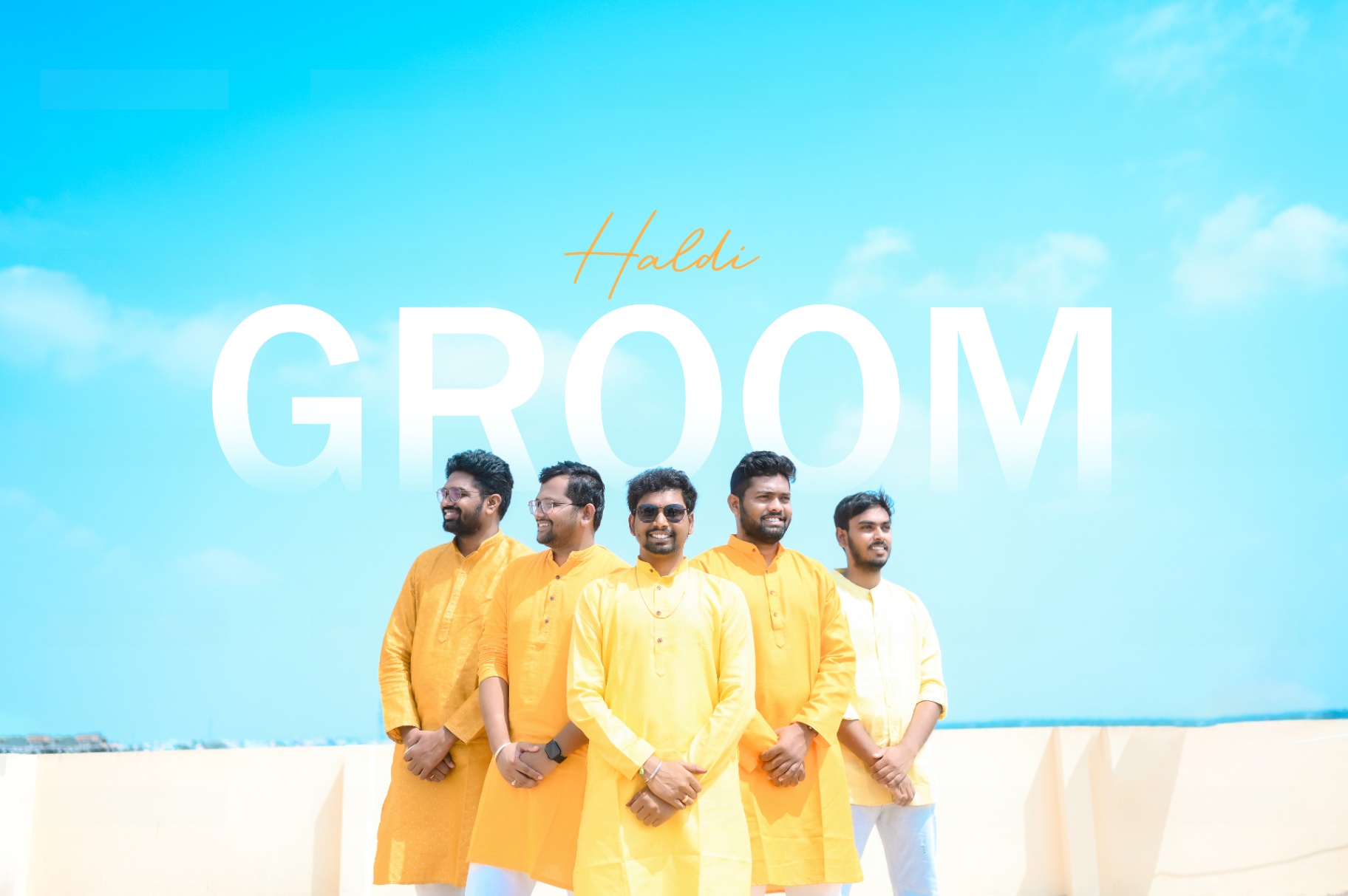 Groom and friends in yellow kurtas during a haldi celebration under a bright blue sky