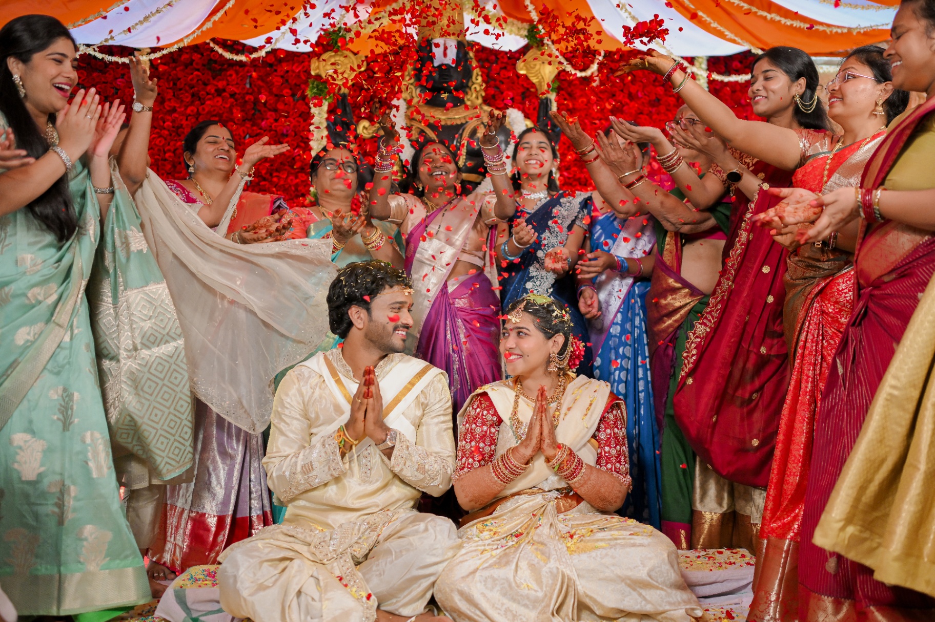 Bride and groom showered with rose petals by family at a temple wedding
