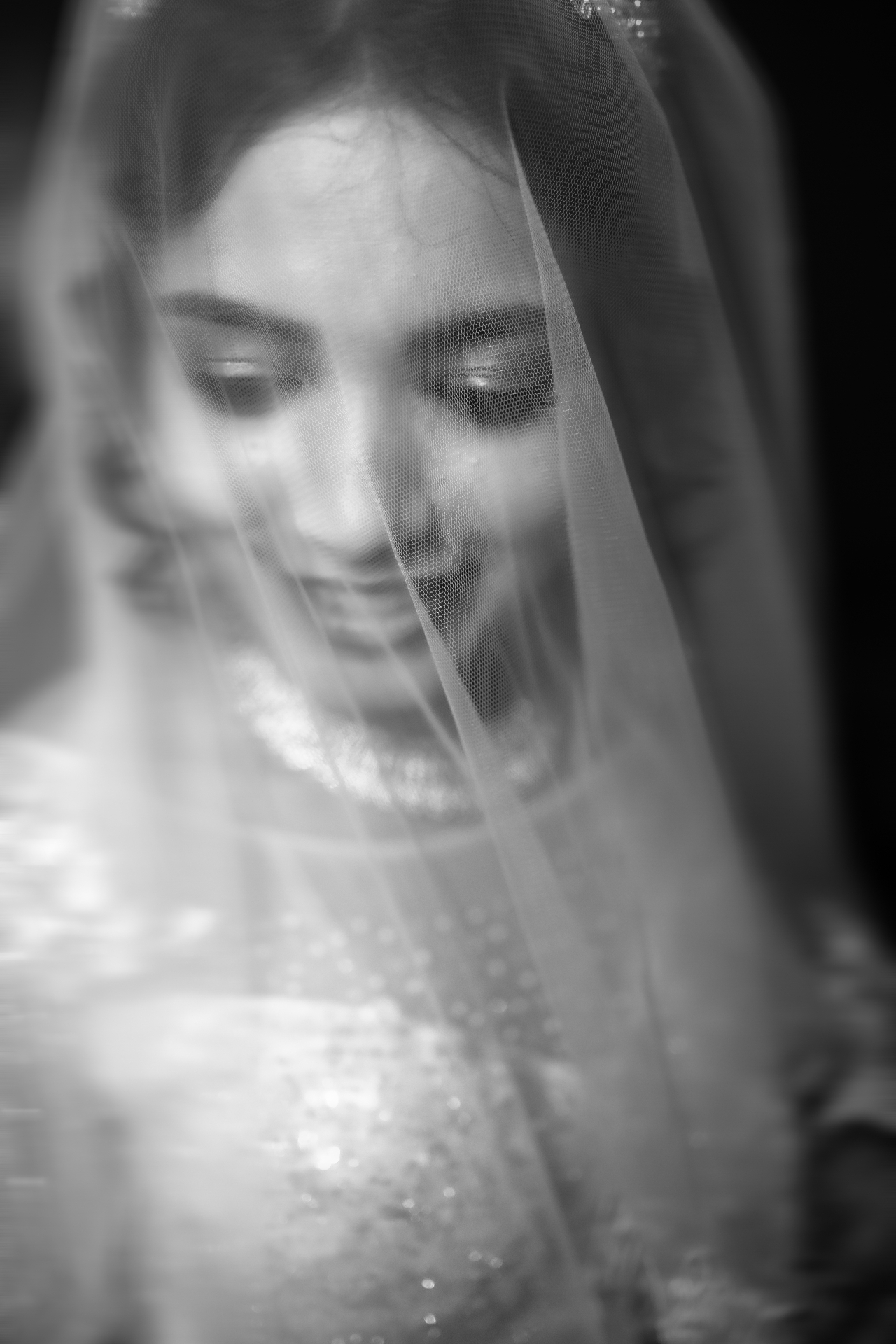 Soft black and white close portrait of a bride smiling through her veil