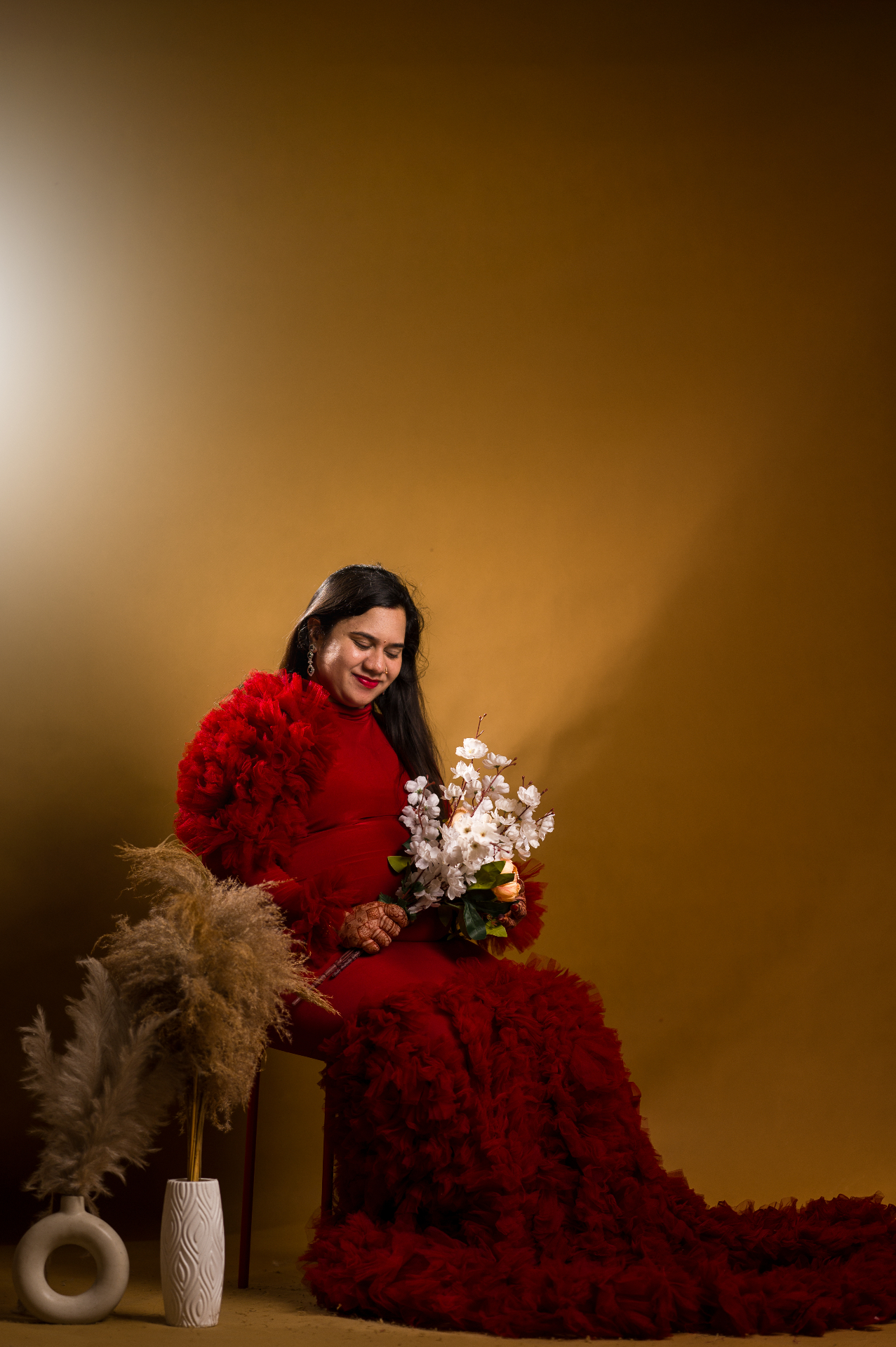 Expecting mother seated with flowers during a maternity photo session