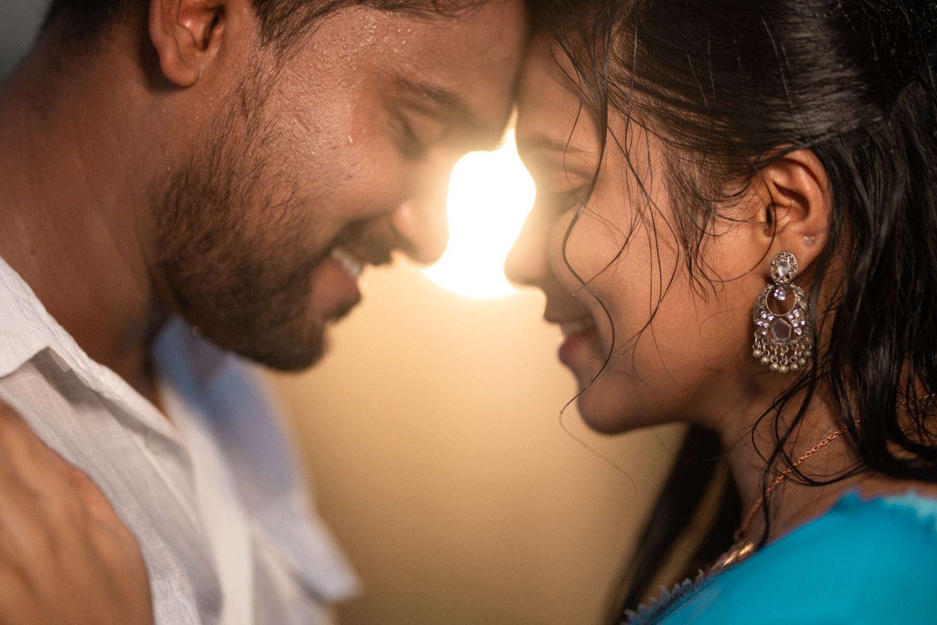 Intimate close up portrait of a couple foreheads touching in warm light