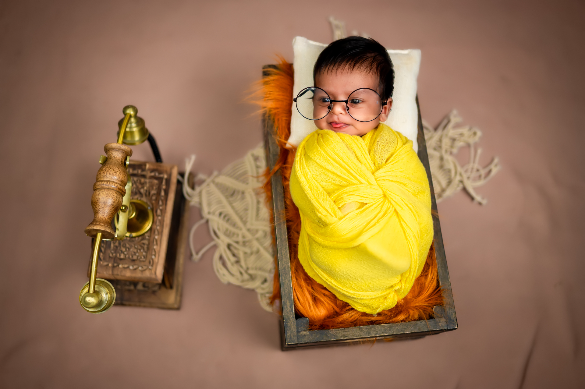 Baby wrapped in yellow cloth wearing oversized glasses