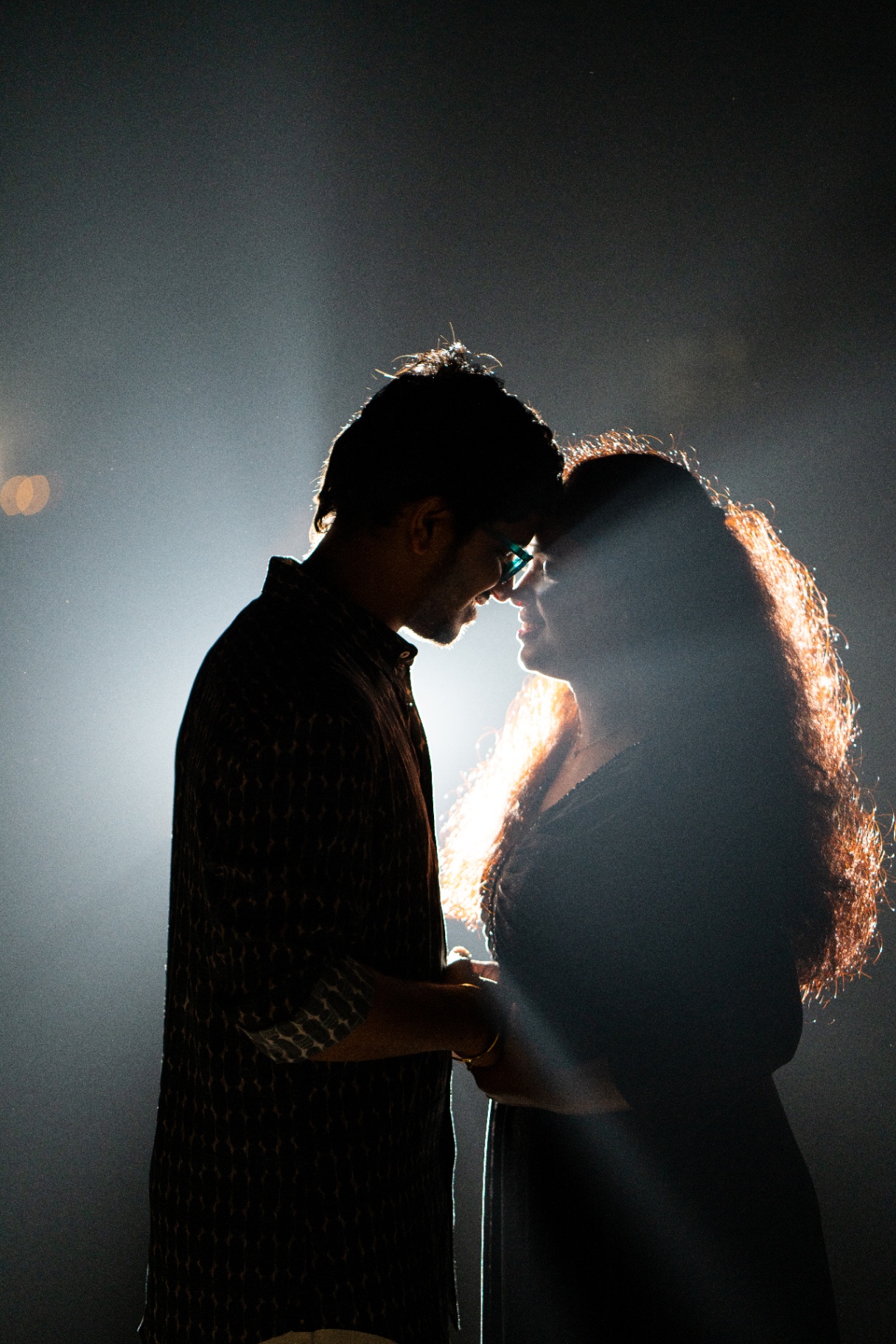 Backlit silhouette of a couple holding each other in a smoky studio scene