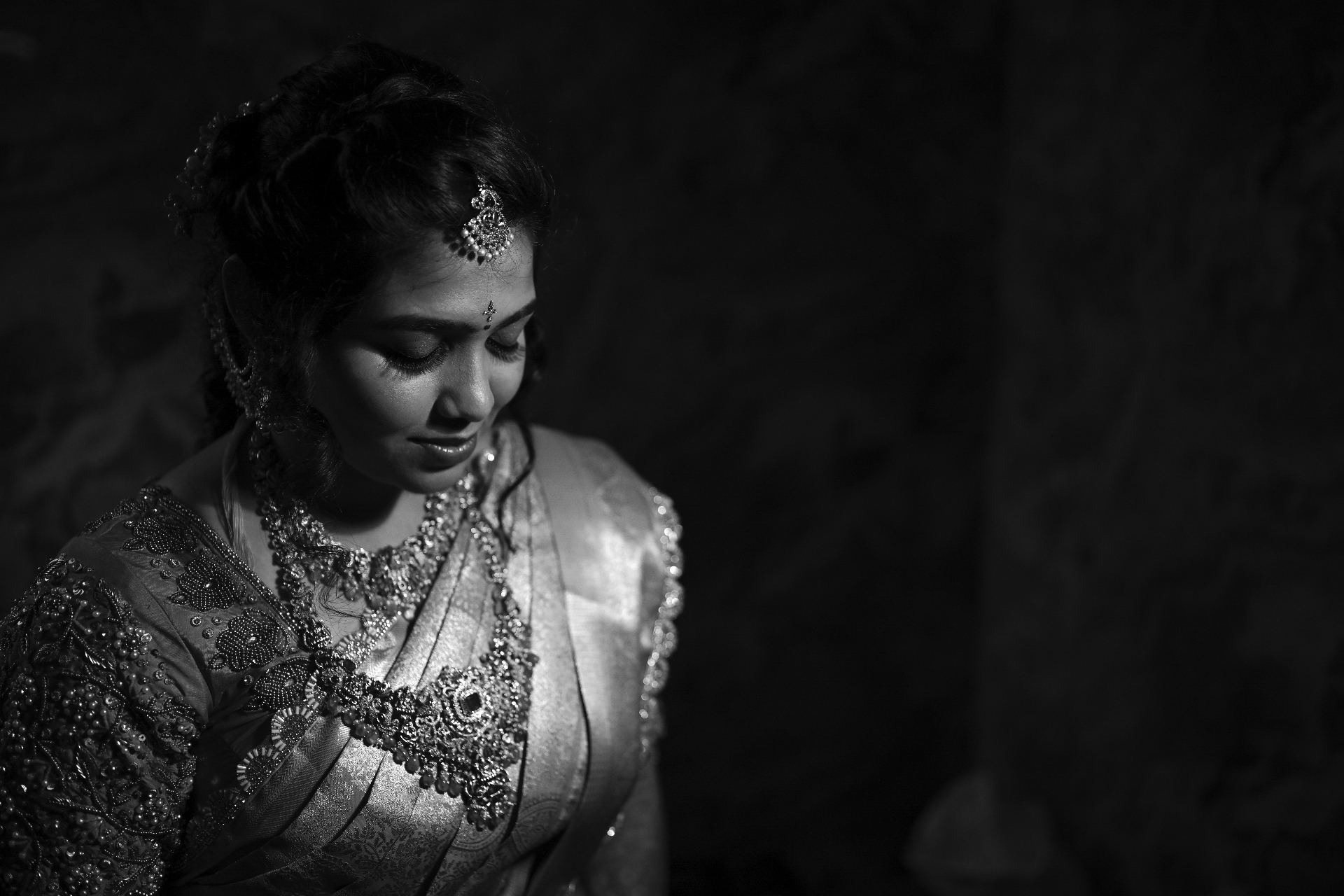 Black and white portrait of a bride in heavy bridal jewellery looking down